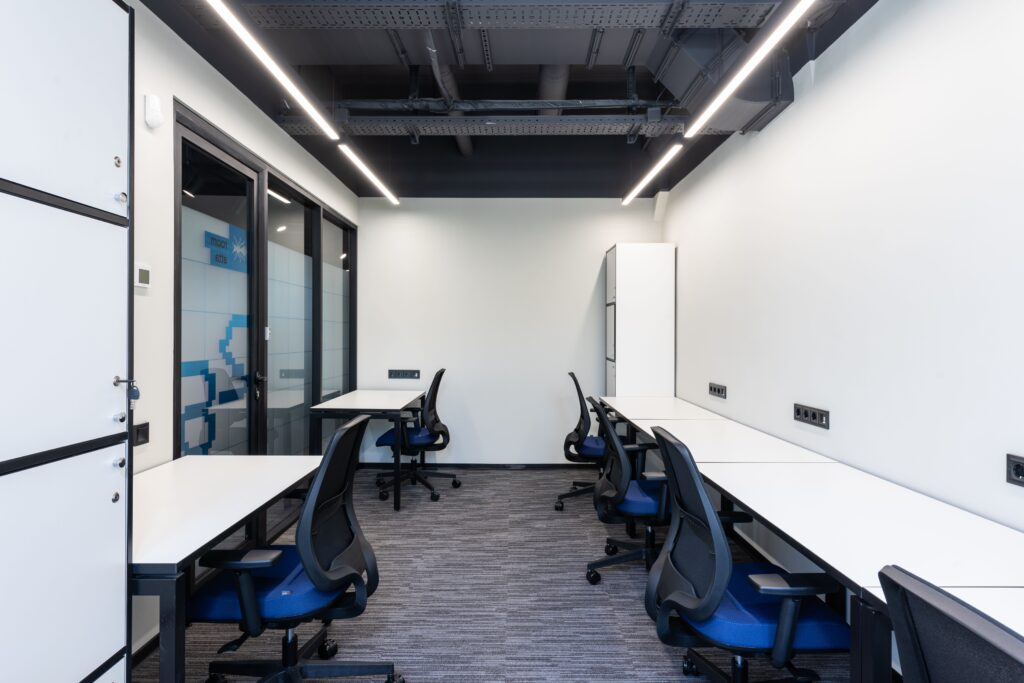 Interior of light contemporary office with tables with chairs next to glass door and wall