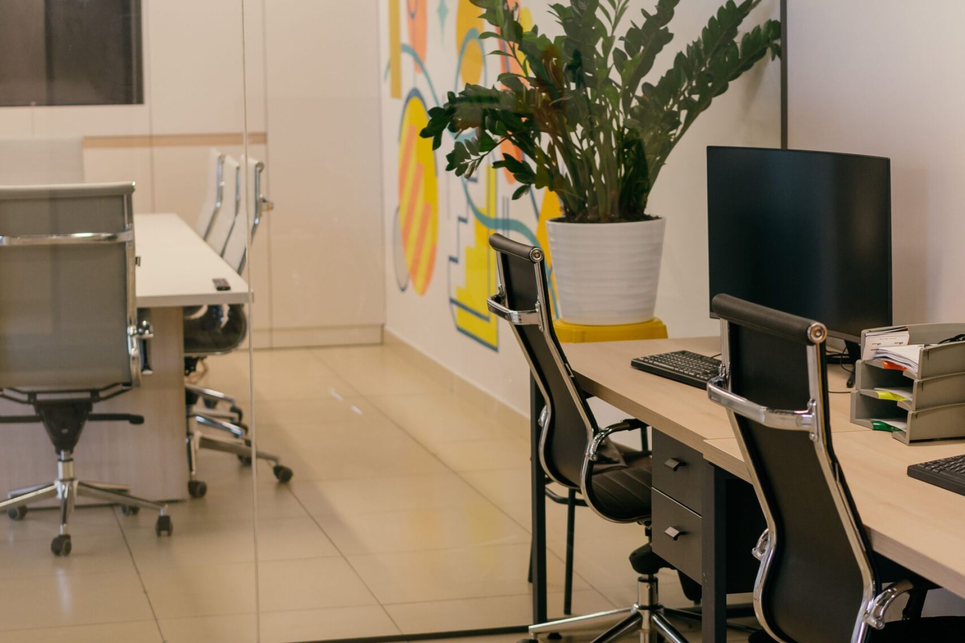 Spacious and contemporary office interior with glass partitions, stylish furniture, and vibrant wall art.